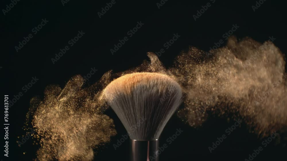 Super slow motion macro shot of makeup brush and golden shiny face powder shake at 1000 fps. Elegant luxury make up cosmetic abstract background. Beauty make-up glitter flying in high speed close up