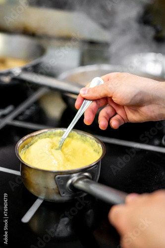 A person stirs a creamy mixture in a saucepan on a stove, capturing the warmth and diligence of cooking