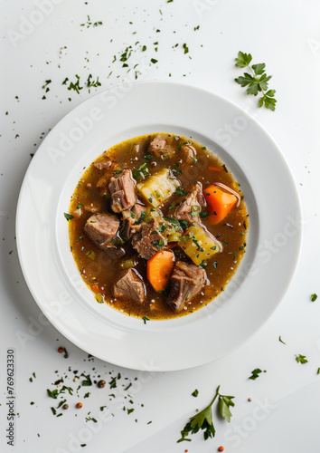 lamb soup with meat, potato and carrots in the white bowl standing on the white table, close-up