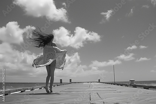 girl in a swim coverup blowing in the wind on a pier photo