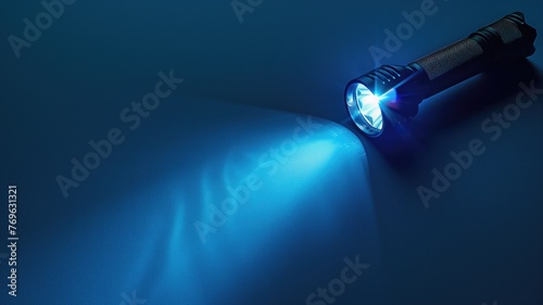 A flashlight turned on casting a bright blue beam of light against dark background.