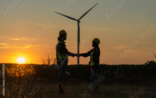 Engineer and energy farming. Wind turbine with the silhouette of sunset background.