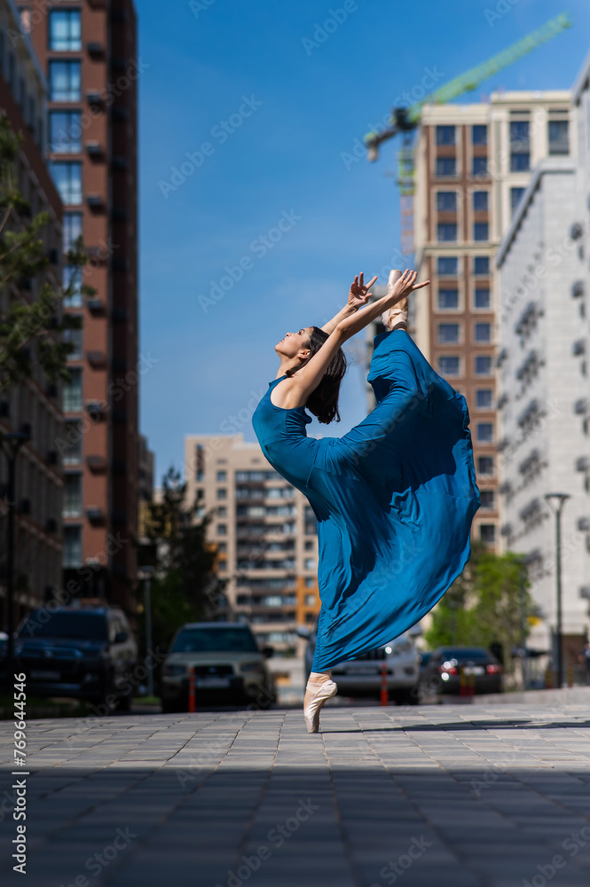 Beautiful Asian ballerina dancing outdoors. Urban landscape.