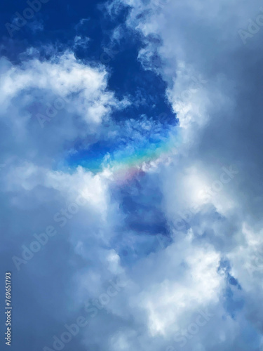 A rainbow in a ray of sunlight between clouds