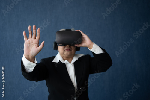 Senior Business woman wearing smart virtual glassest for Video conference, VR  headset glasses technology in modern offices and posing finger pointing and touching. Metaverse concept.