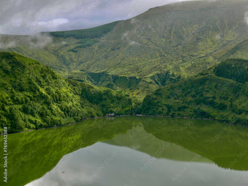 area of Lagoa Funda (deep lagoon) and Lagoa Rasa (shallow lagoon) on Flores island, Azores, covered in deep Fog and low clouds and lush greenery. Reflections of volcanic crater on lakes