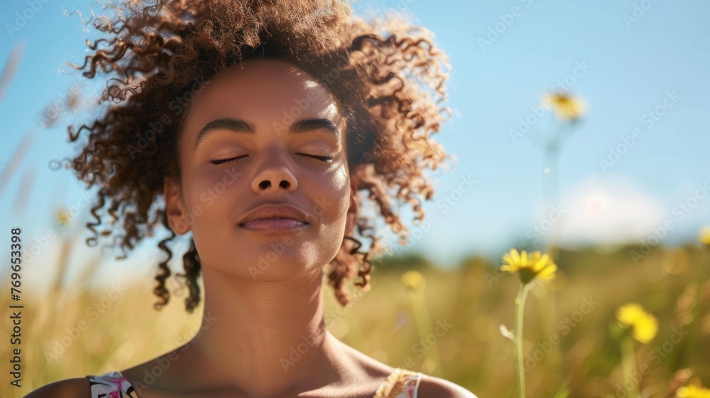 A woman with curly hair eyes closed and a peaceful expression standing in a field of tall grass with yellow flowers under a clear blue sky. A woman with curly hair eyes closed and a peaceful expression standing in a field of tall grass with yellow flowers under a clear blue sky.