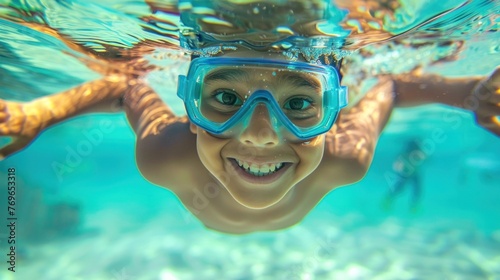 Young boy with blue goggles smiling underwater.