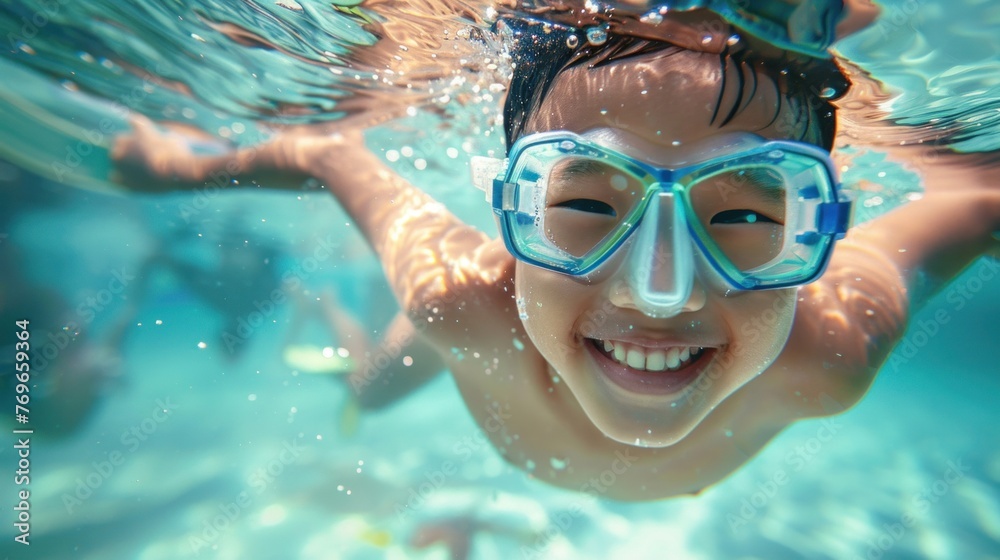 A joyful young boy wearing a snorkel mask smiling underwater surrounded by bubbles and the blue expanse of the sea.