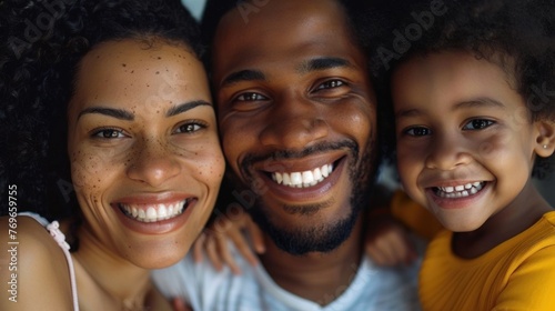A joyful family of three a man a woman and a young girl smiling brightly and posing closely together for a portrait.