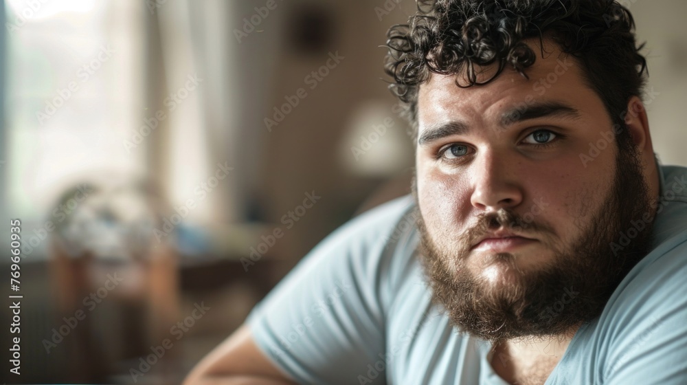Man with curly hair and beard wearing a blue shirt looking contemplative with a slight frown. Man with curly hair and beard wearing a blue shirt looking contemplative with a slight frown.