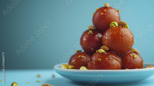 Gulab Jamun, soaked in rose syrup, garnished with almonds and pistachio on a ceramic plate