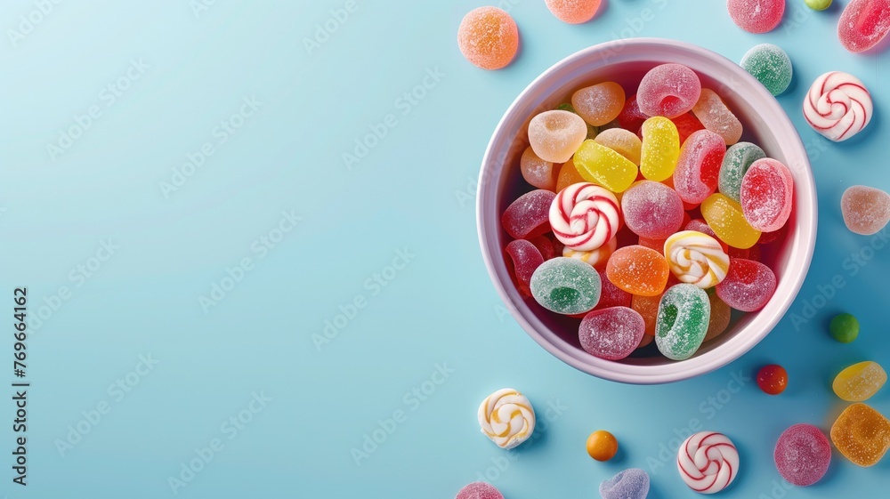 A bowl filled with colorful candies on a blue background, including gummy and swirl lollipops.