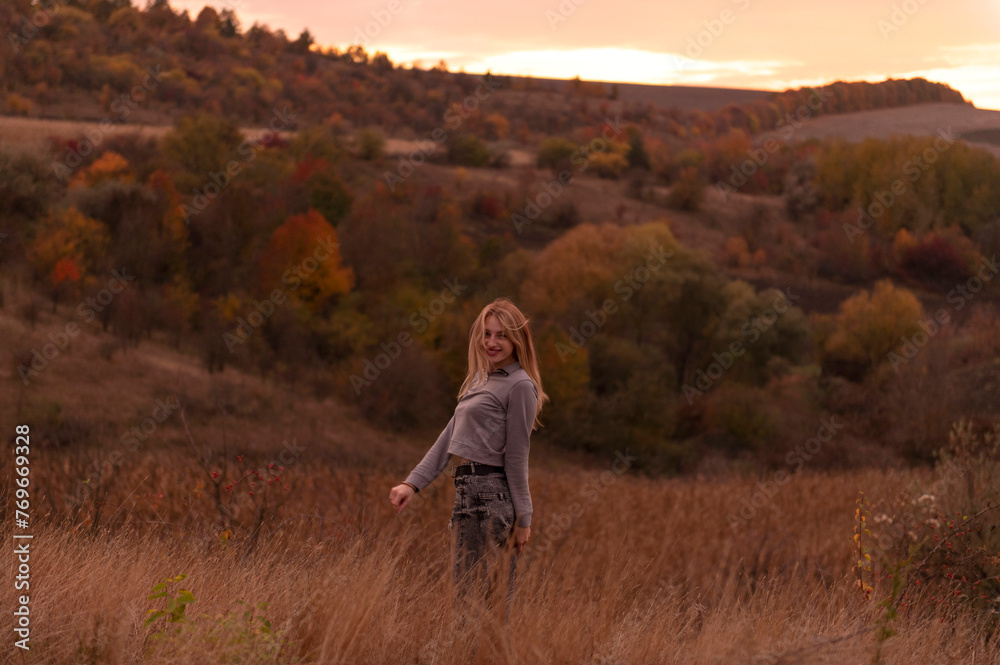 Young attractive blonde woman standing on the hill at sunset Young attractive blonde woman standing on the hill at sunset