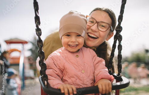 Smiling mother and daughter having good time on the playground