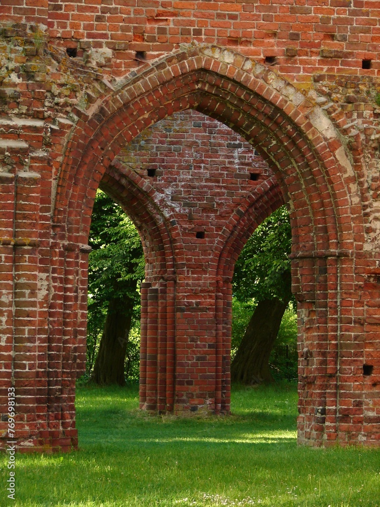 Arched brick entryway to the Eldena Monastery on a lush, verdant grassland