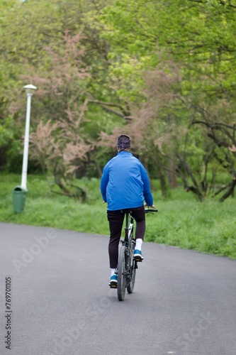 Young adult cyclist leisurely riding a bicycle down a rural road surrounded by trees