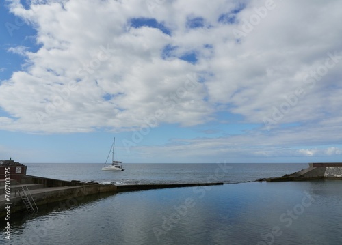 a white boat is docked near the shore at the ocean