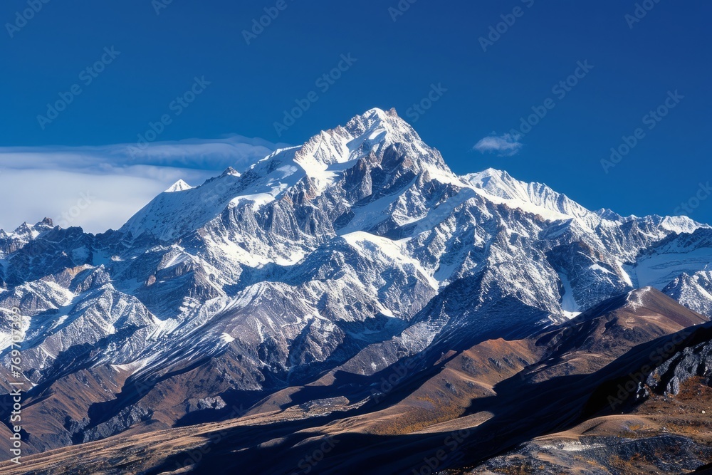A scenic view of snow-covered mountain peaks against a clear blue sky, highlighting the rugged beauty of the alpine landscape