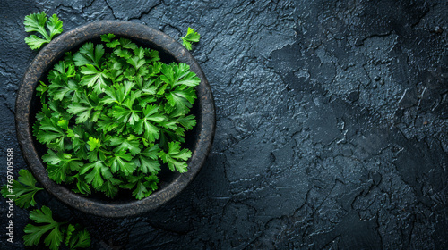 A bowl of parsley is sitting on a black countertop. The image has a simple and clean look, with the parsley being the main focus
