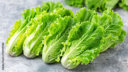 A bunch of green lettuce is on a table. The lettuce is fresh and crisp. The table is made of concrete