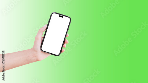 Close-up of hand holding smartphone with blank on screen isolated on background of green.