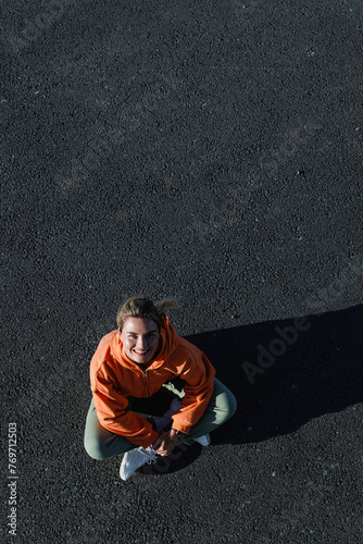 Top view of a young adult woman wearing activewear, sitting on the asphalt © blackday