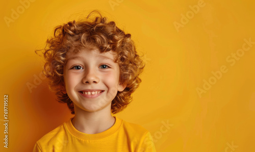 A happy child boy on a yellow studio background