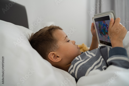  Toddler Boy Engrossed in Tablet Technology in Bed