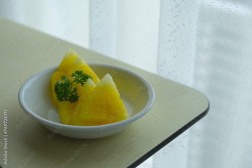 Delicious yellow watermelon on small plate with window as background. Semangka