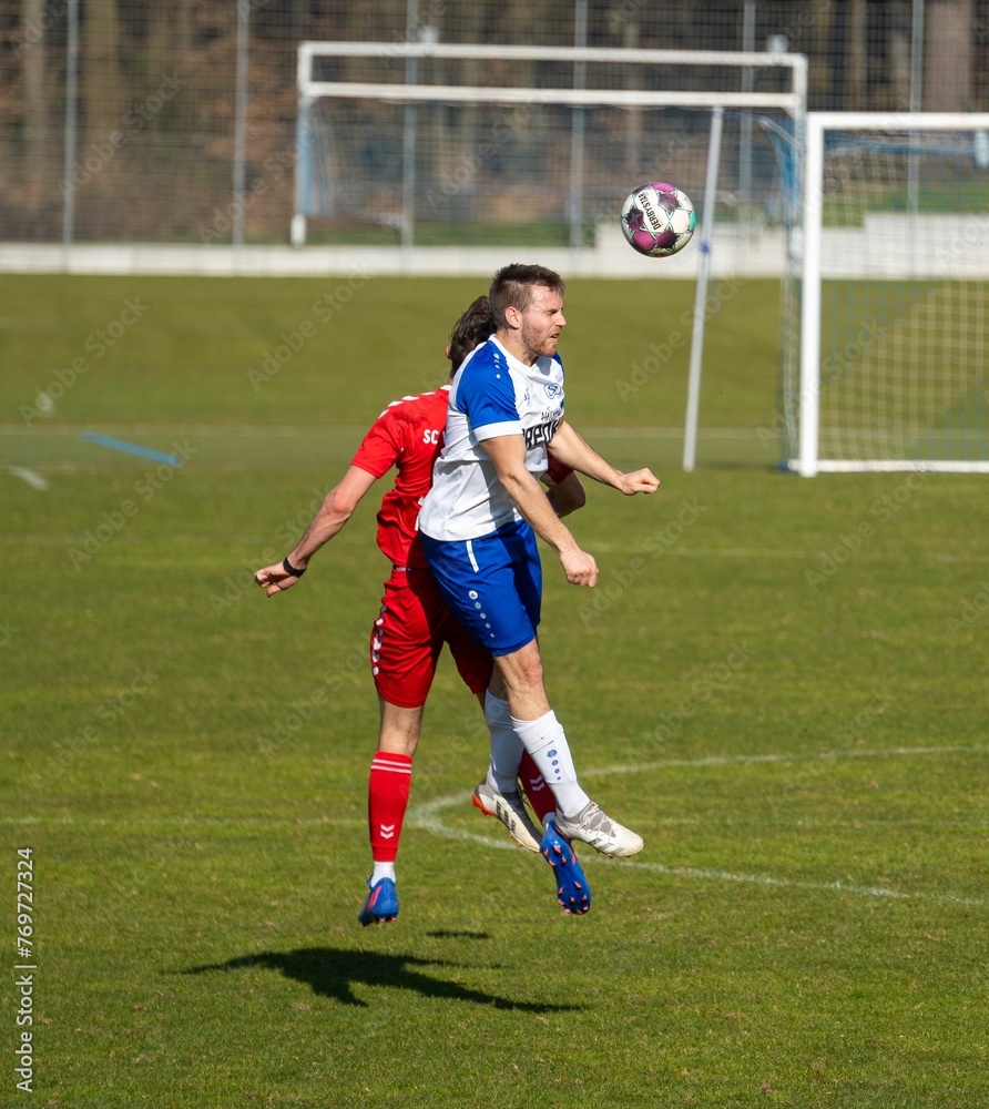 Obraz premium Football players in the motion of jumping, trying to catch the ball in the green field