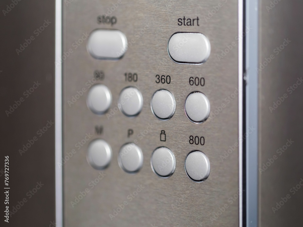 Closeup of an appliance control panel buttons on a metal surface Closeup of an appliance control panel buttons on a metal surface