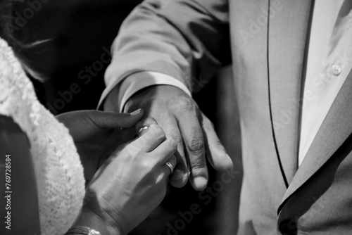 Close-up shot of a newlywed couple putting rings on hands at a wedding ceremony © Wirestock