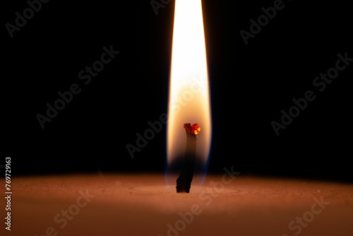 Closeup of a candle burning brightly in a dark room