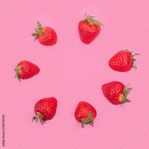 Whole ripe red strawberries are laid out in a circle on a pink background. Red ripe strawberries background. © Alena