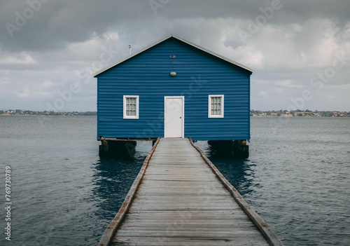 Wooden dock leading right to a small blue house on the water
