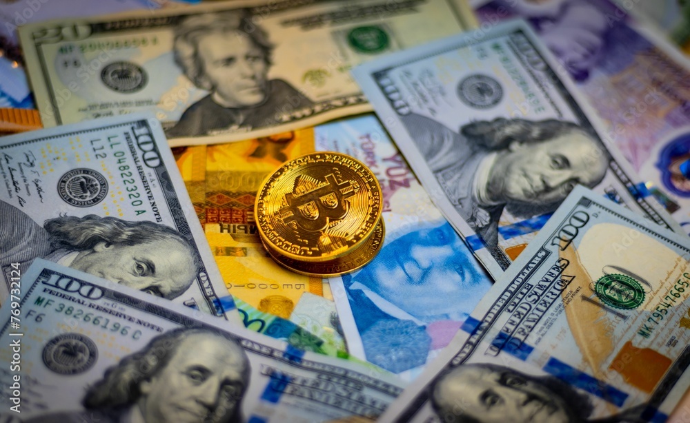 Closeup shot of a golden Bitcoin cryptocurrency token placed atop a stack of banknotes.