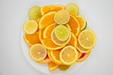 White plate with several slices of citrus fruits on a white background