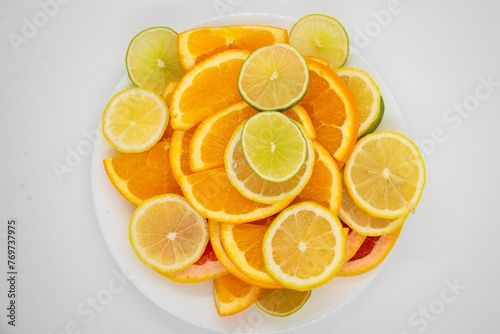 White plate with several slices of citrus fruits on a white background