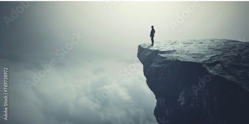 A man stands on a cliff overlooking a cloudy sky