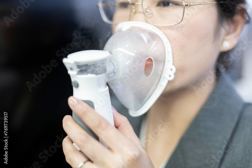 A woman holds a nebulizer for inhalation treatment