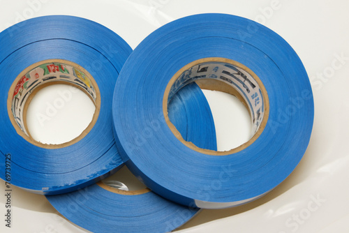 blue electrical tape. three round packages with blue electrical tape lie on a white table, top view, close-up, items concept photo