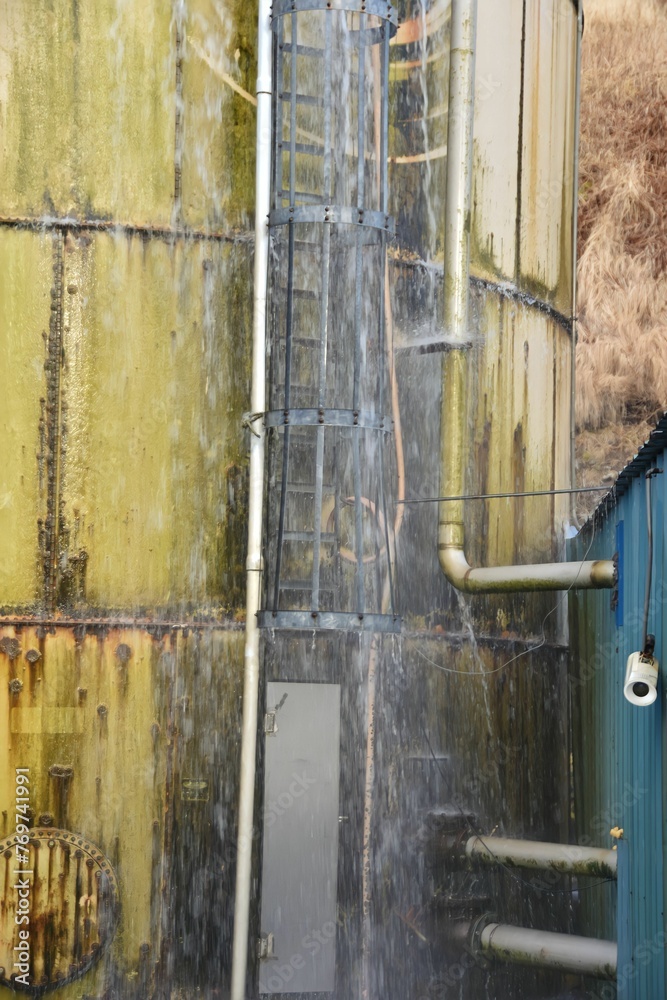 Naklejka premium Old metal water tank shown next to a broken security camera
