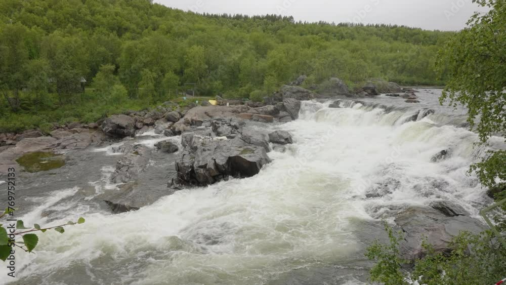 Dynamic view of powerful river rapids with a backdrop of dense greenery in a serene landscape in Estonia Dynamic view of powerful river rapids with a backdrop of dense greenery in a serene landscape in Estonia