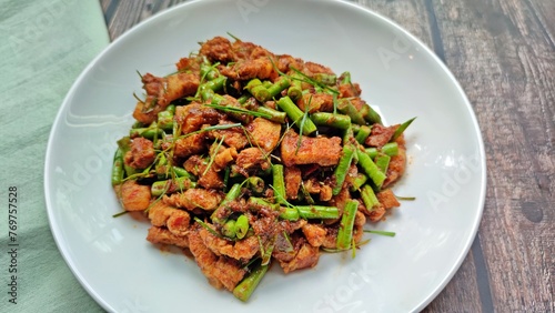 Stir fried crispy pork belly and yard long bean with ginger red curry paste, Authentic Thai food.