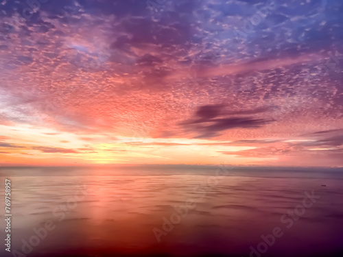Aerial view of the sunrise over the Atlantic Ocean with orange, red, and purple highlights