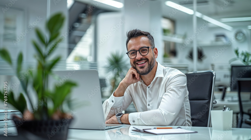 jeune homme souriant dans un bureau en train de téléphoner assis devant son ordinateur jeune homme souriant dans un bureau en train de téléphoner assis devant son ordinateur