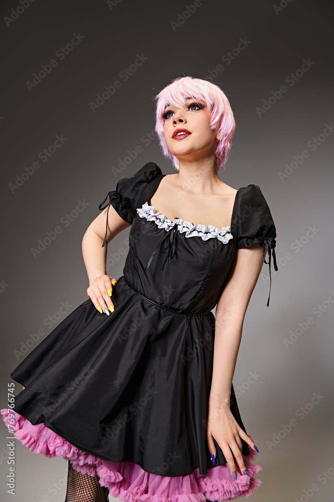 beautiful pink haired cosplayer in sexy maid costume posing on gray backdrop and looking away beautiful pink haired cosplayer in sexy maid costume posing on gray backdrop and looking away
