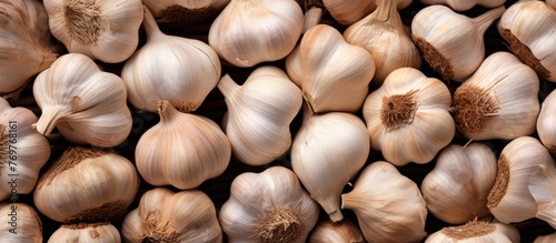 A pile of garlic bulbs, a popular ingredient in cuisine, sitting on a table. Garlic is a natural food known for its flavorful addition to dishes and is considered a superfood