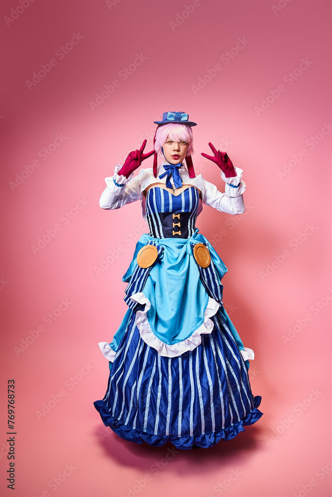 beautiful chic female cosplayer showing peace gesture and looking at camera on pink backdrop